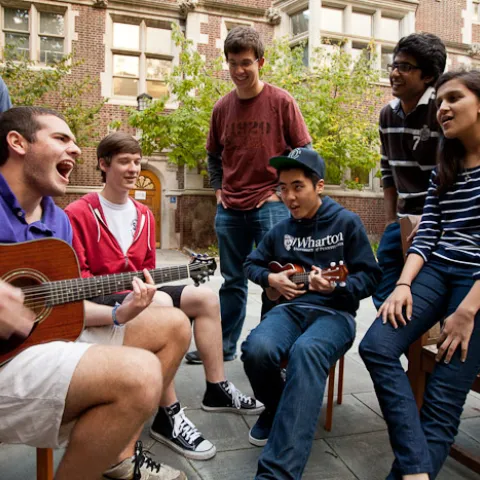 Students sit around a guitar player on the Junior Balcony