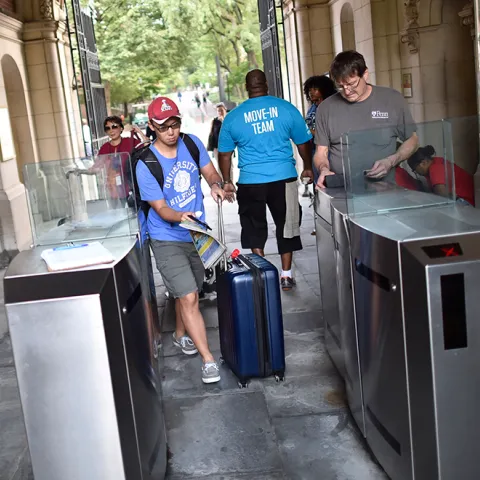 Students enter the Quad with luggage