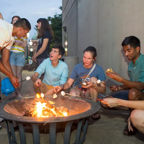 Stouffer residents roast marshmallows and converse around a firepit on the Stouffer patio