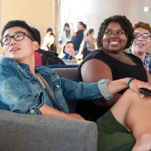 Several Penn undergrads sit together on a couch in a room full of students.