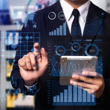 A business man in a business suit holding a business tablet and tapping on digital business images.  Business.