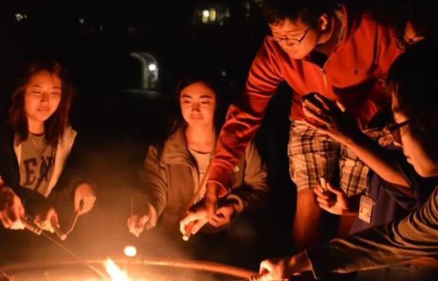 Students roast marshmallows over a firepit in the Quad