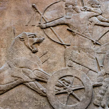 An ancient bas-relief of a king shooting a lion from a chariot with a bow