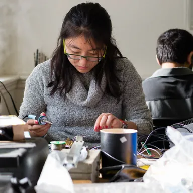 A woman soldering in Kings Court English's maker room